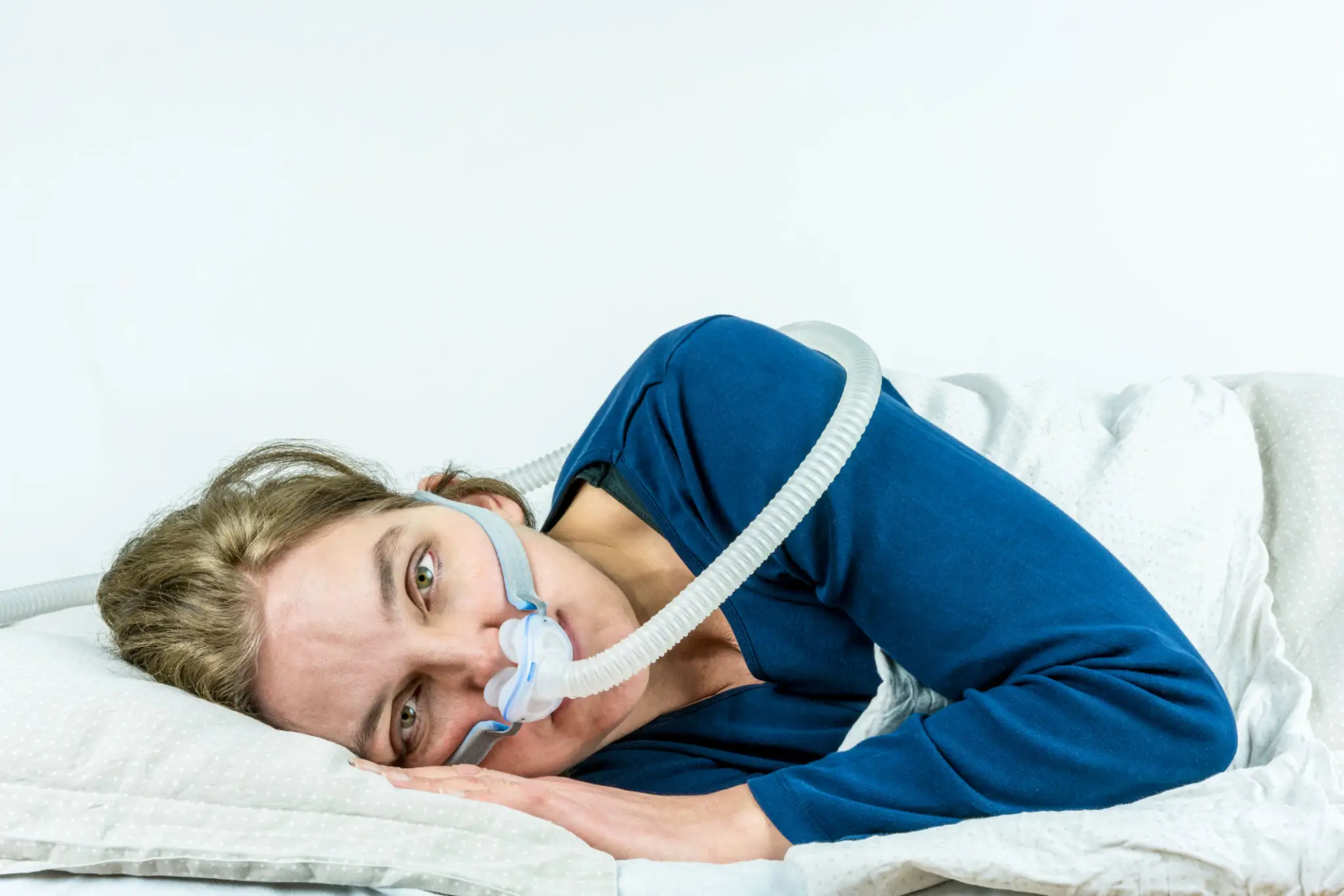 681b937c41c3b_Wide-Awake-cpap A woman laying in bed with her head down.