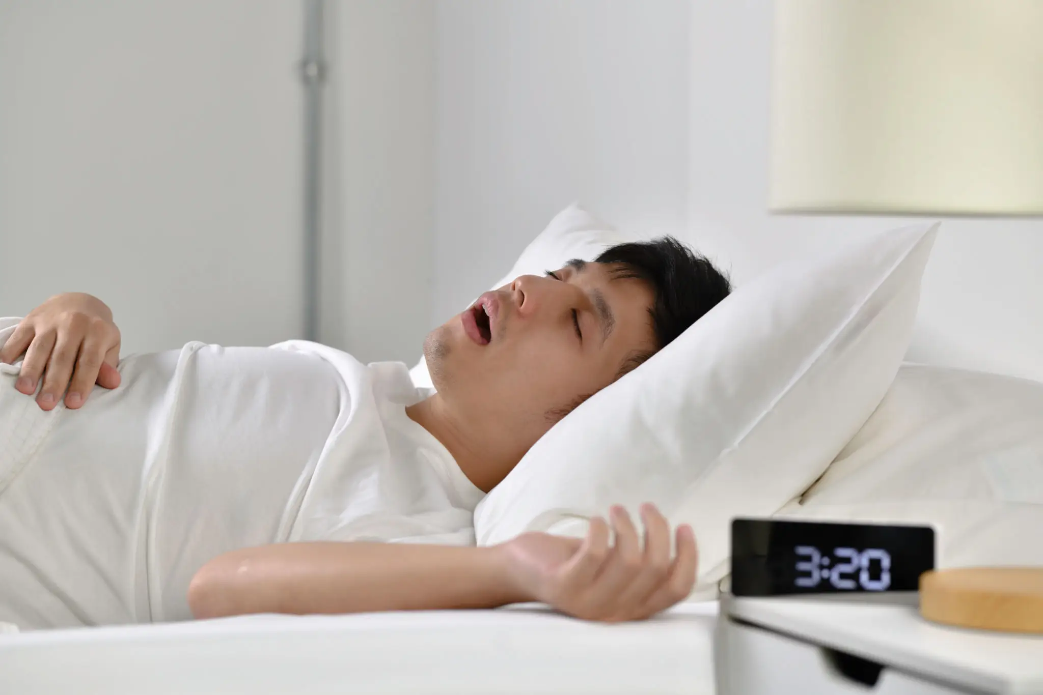 A man laying in bed with his eyes closed.