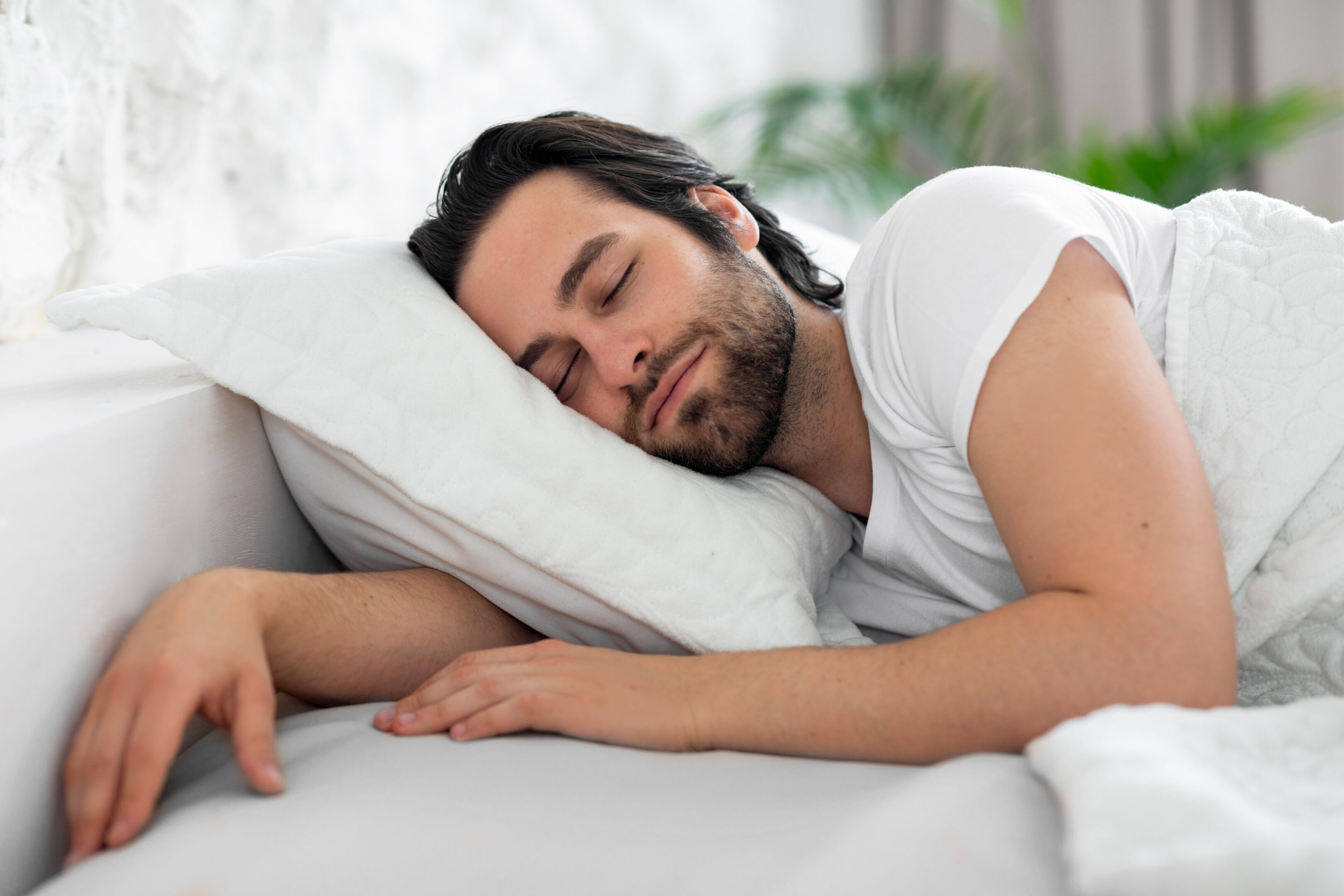 A man sleeping on his stomach in bed.